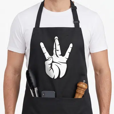 Tablier de cuisine noir avec une illustration blanche représentant une main faisant un signe à trois doigts tracée en style graphique.