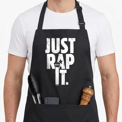 Tablier de cuisine noir avec inscription Just Rap It et illustration de microphone blanc stylisé.