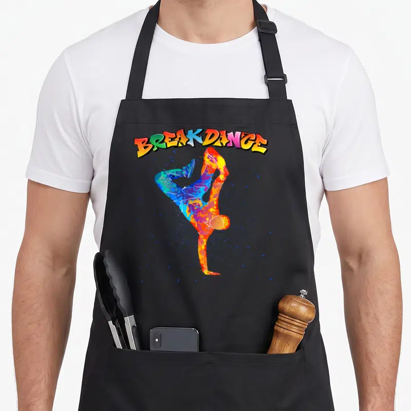Tablier de cuisine noir avec illustration multicolore d'un danseur en pose de breakdance et texte BREAKDANCE en style graffiti.