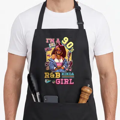 Tablier de cuisine noir avec illustration colorée d'une femme aux cheveux bouclés, lunettes de soleil et cassettes audio vintage.