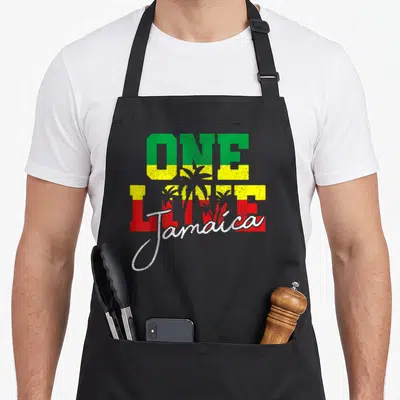 Tablier de cuisine noir avec inscription One Love Jamaica aux couleurs vert jaune rouge et silhouettes de palmiers