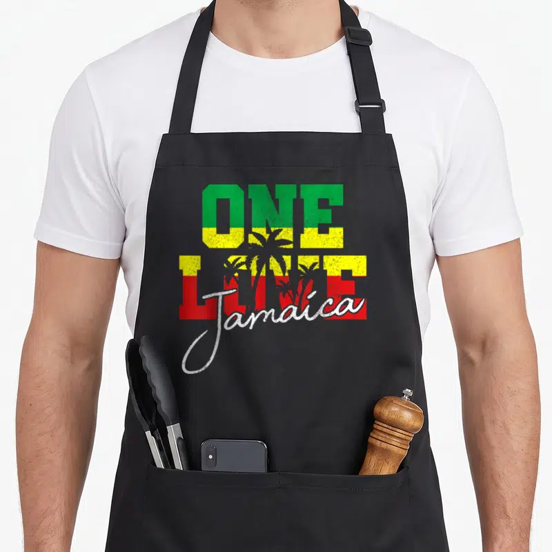 Tablier de cuisine noir avec inscription One Love Jamaica aux couleurs vert jaune rouge et silhouettes de palmiers