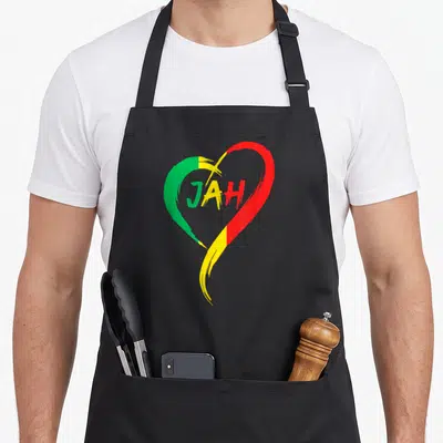 Tablier de cuisine noir avec un grand cœur aux couleurs vert jaune et rouge portant le mot Jah au centre.