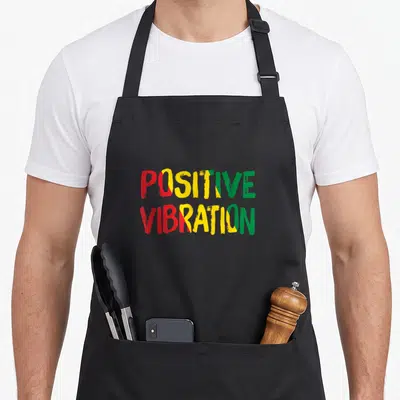 Tablier de cuisine noir avec l'inscription Positive Vibrations en rouge jaune et vert