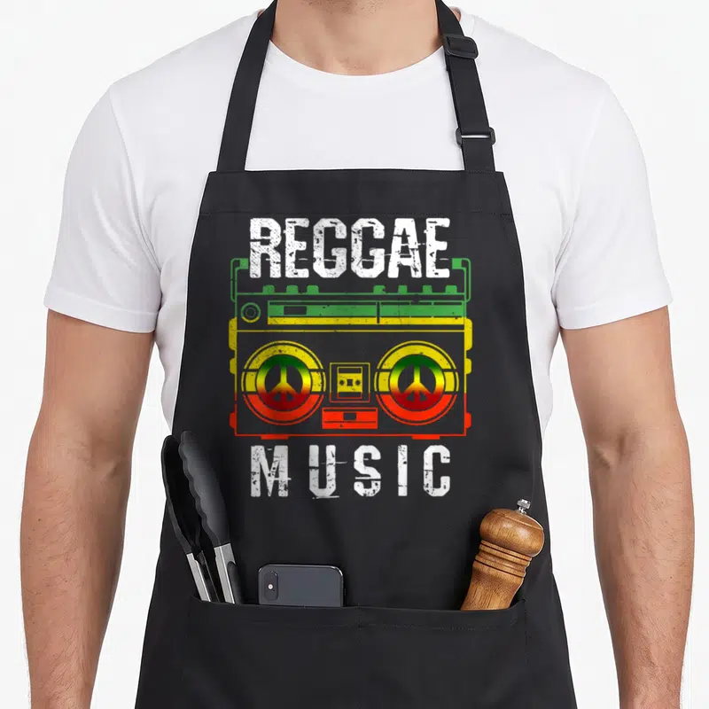 Tablier de cuisine noir avec une illustration de boombox aux couleurs vert jaune rouge et les mots REGGAE MUSIC en blanc.