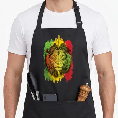 Tablier de cuisine noir avec un lion rastafari aux couleurs vert jaune et rouge en arrière-plan texturé.