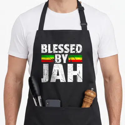 Tablier de cuisine noir avec inscription Blessed by Jah et bandes vertes jaunes rouges texturées
