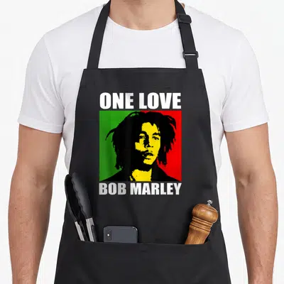 Tablier de cuisine noir avec portrait stylisé de Bob Marley et texte One Love en blanc.