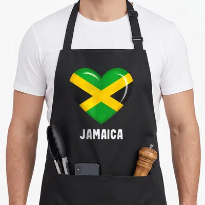 Tablier de cuisine noir avec un grand cœur aux couleurs du drapeau jamaïcain et le mot JAMAICA en blanc en dessous.