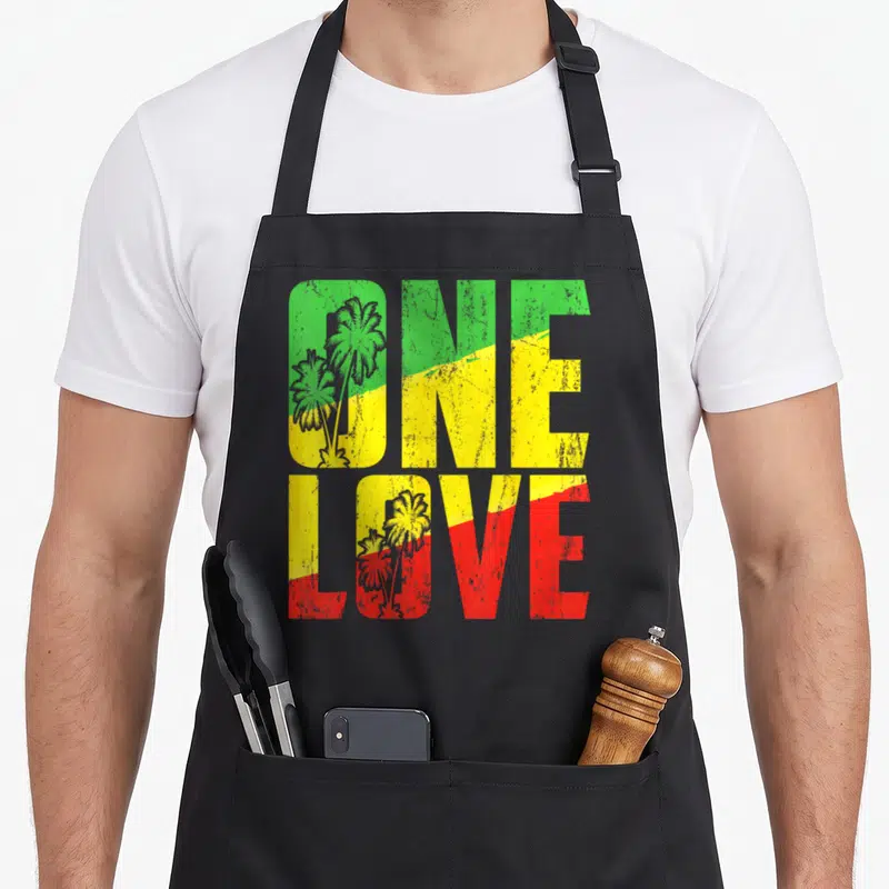 Tablier de cuisine noir avec l'inscription One Love aux couleurs vert jaune et rouge du drapeau jamaïcain.