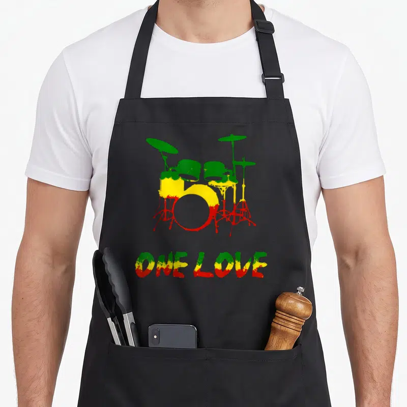 Tablier de cuisine noir avec illustration de batterie aux couleurs vert jaune rouge et texte One Love en bas.