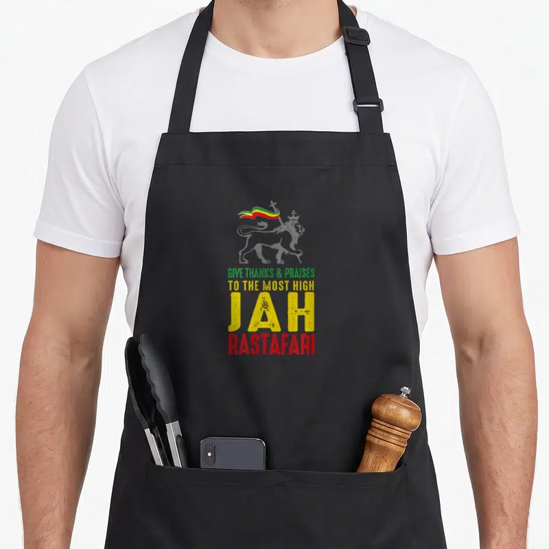 Tablier de cuisine noir avec un lion couronné et les mots Give Thanks Praises Jah Rastafari aux couleurs du drapeau.
