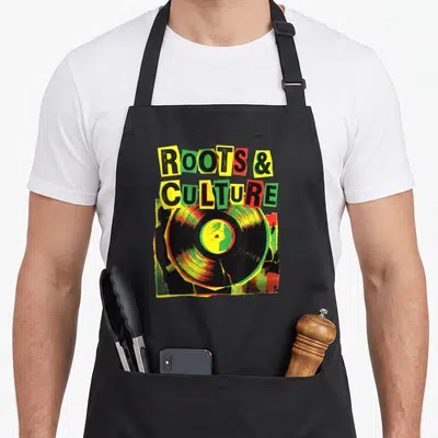 Tablier de cuisine noir avec illustration vinyle et texte Roots & Culture aux couleurs reggae.