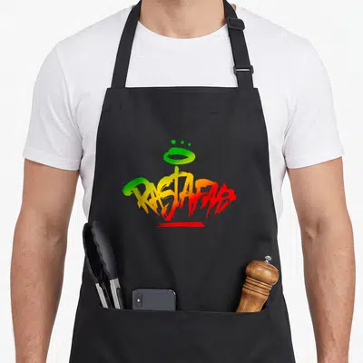 Tablier de cuisine noir avec inscription Rastafari en graffiti multicolore vert jaune et rouge sur le devant.