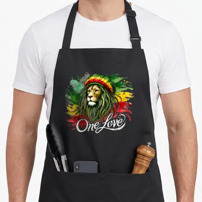 Tablier de cuisine noir avec illustration d'un lion portant un bonnet aux couleurs reggae et le texte One Love en blanc.