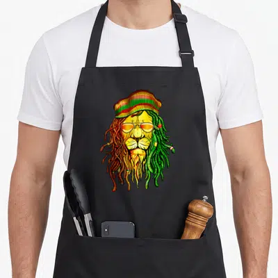 Tablier de cuisine noir avec un lion aux dreadlocks verts et roux, coiffé d'un béret tricolore et de lunettes de soleil.