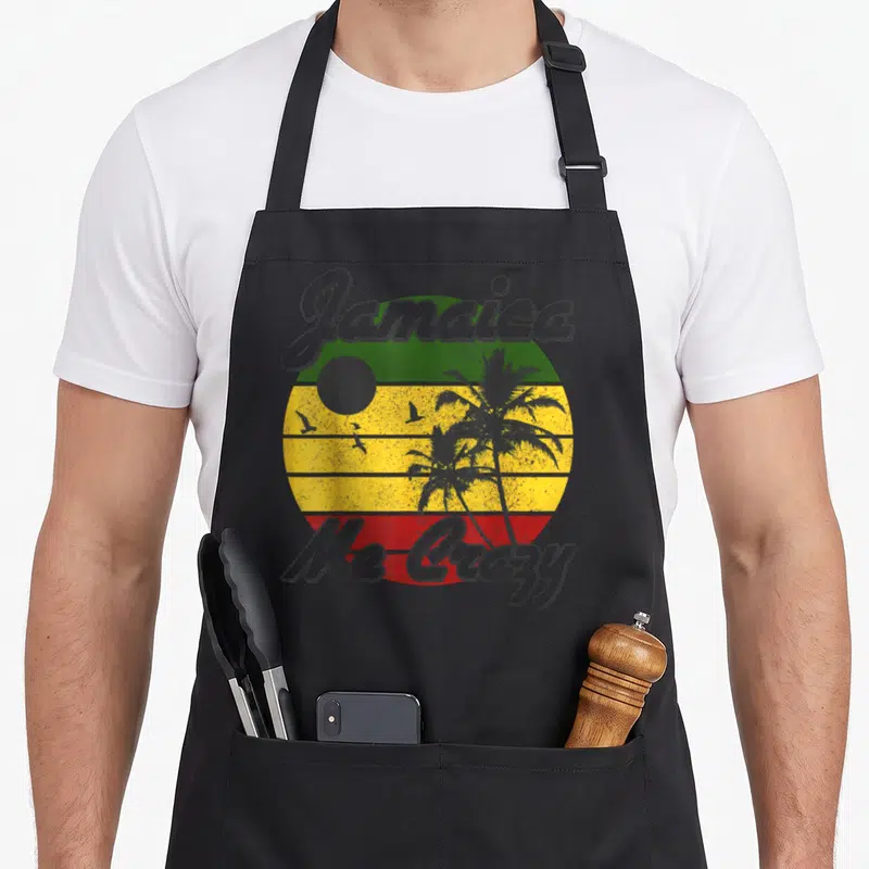 Tablier de cuisine noir avec illustration circulaire Jamaica Me Crazy aux couleurs reggae et silhouettes de palmiers