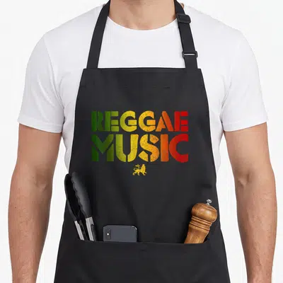 Tablier de cuisine noir avec inscription Reggae Music aux couleurs vert jaune rouge et un petit lion couronné jaune en dessous.