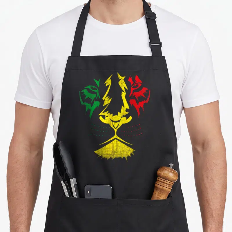 Tablier de cuisine noir avec un visage de lion Rastafari aux couleurs vert jaune et rouge en style graphique déstructuré