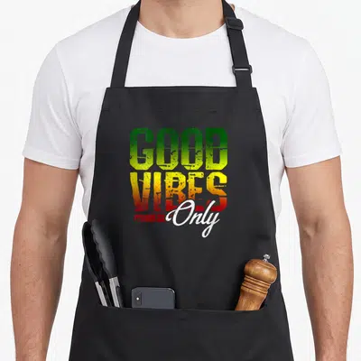 Tablier de cuisine noir avec l'inscription « Good Vibes Only » aux couleurs rastafari vert jaune et rouge.