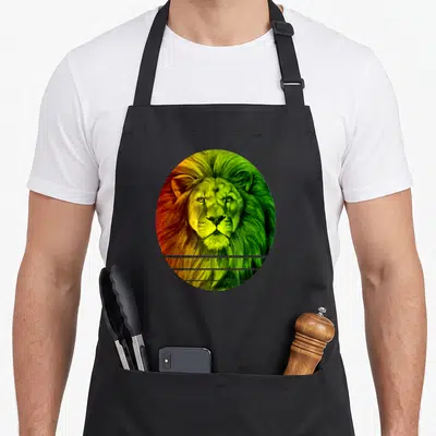 Tablier de cuisine noir avec un lion aux couleurs Rasta encadré dans un ovale aux teintes vert jaune et rouge.