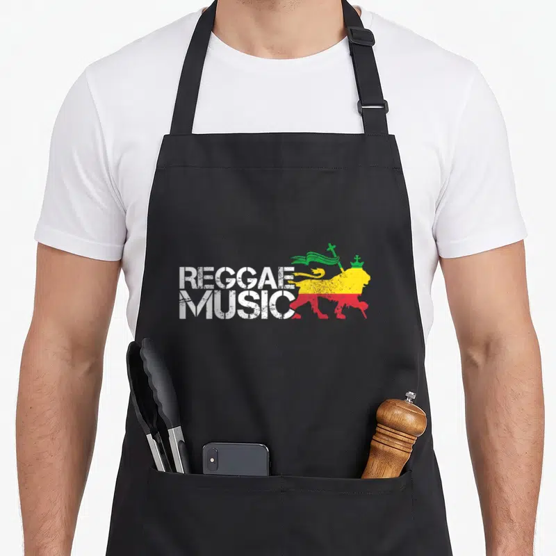 Tablier de cuisine noir avec illustration Lion de Judah tricolore et texte Reggae Music en blanc.