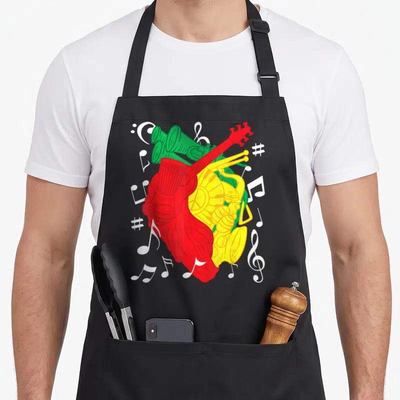 Tablier de cuisine noir avec un cœur musical aux couleurs vert rouge jaune et notes blanches dispersées.