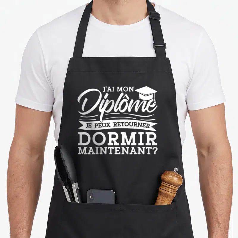 Tablier de cuisine noir avec inscription blanche J'ai mon diplôme Je peux aller dormir maintenant et une casquette d'étudiant.