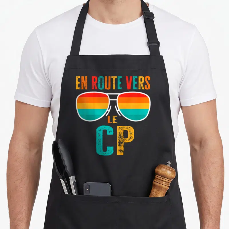 Tablier de cuisine noir avec lunettes arc-en-ciel et texte En route vers le CP en lettres colorées vintage.
