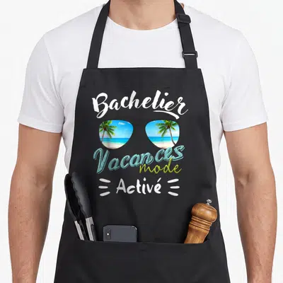 Tablier de cuisine noir avec lunettes de soleil reflétant des palmiers et le texte Vacances mode activé.
