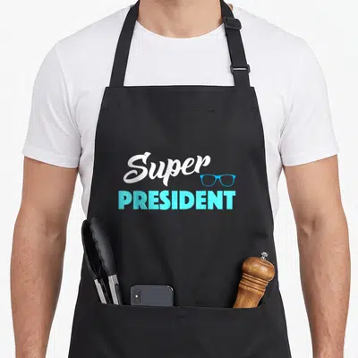 Tablier de cuisine noir avec l'inscription Super President et un motif de lunettes de vue bleues sur le devant.