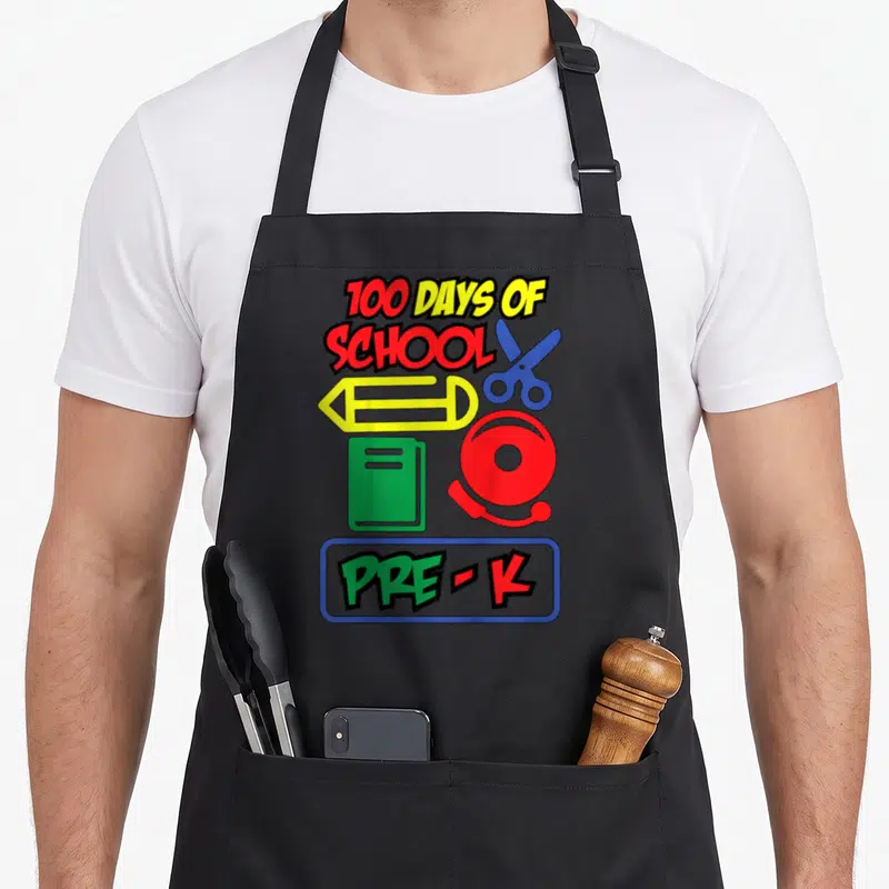 Tablier de cuisine noir avec motifs d'école colorés incluant ciseaux, crayon et texte 100 days of school Pre-K