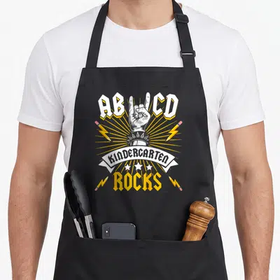 Tablier de cuisine noir avec illustration main rock, crayons-éclair et texte Kindercarted Rocks en blanc et jaune.