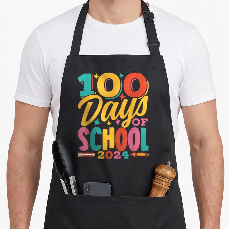 Tablier de cuisine noir avec inscription 100 Days of School 2024 et illustrations de crayons de couleur.