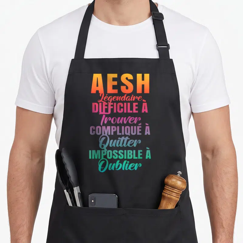 Tablier de cuisine noir avec inscription AESH Légendaire en dégradé de couleurs vives.