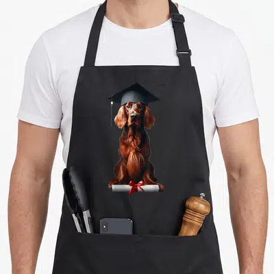 Tablier de cuisine noir avec illustration d'un setter irlandais portant une toque de diplômé et tenant un diplôme noué d'un ruban rouge.