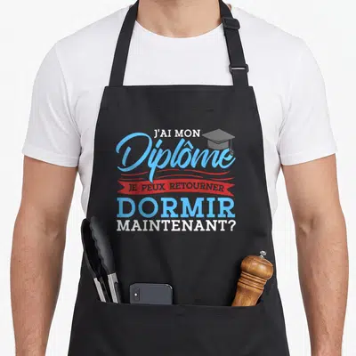 Tablier de cuisine noir avec l'inscription J'ai mon diplôme je peux continuer à dormir maintenant et une toque de graduation bleue.