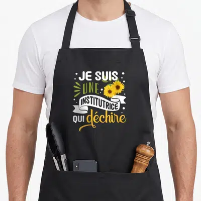 Tablier de cuisine noir avec inscription Je suis une institutrice qui déchire et deux tournesols jaunes.