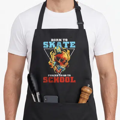 Tablier de cuisine noir avec un crâne de skieur enflammé et le texte Born to Skate Forced to go to School.
