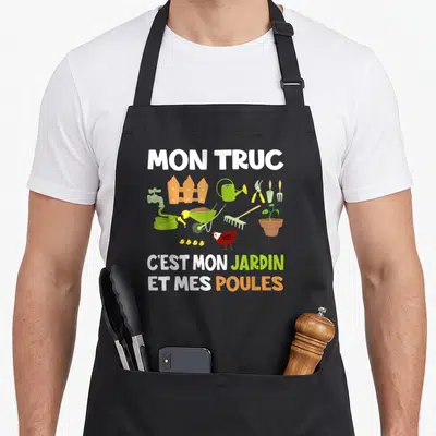 Tablier de cuisine noir avec illustration colorée d'outils de jardinage et une poule accompagnée du texte Mon truc c'est mon jardin et mes poules.