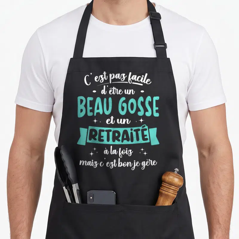 Tablier de cuisine noir avec inscription humoristique sur le statut de retraité et la beauté personnelle en turquoise et blanc.