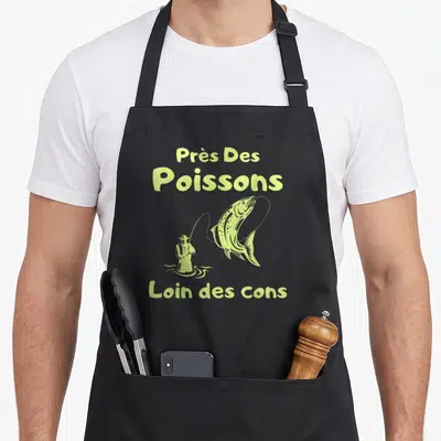 Tablier de cuisine noir avec illustration jaune d'un pêcheur et un saut de poisson, surmonté du texte Près des poissons loin des cons.