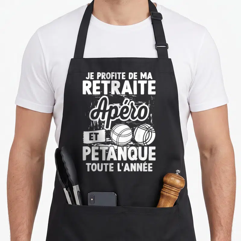 Tablier de cuisine noir avec texte blanc Je profite de ma retraite apéro et pétanque toute l'année et deux boules de pétanque illustrées.