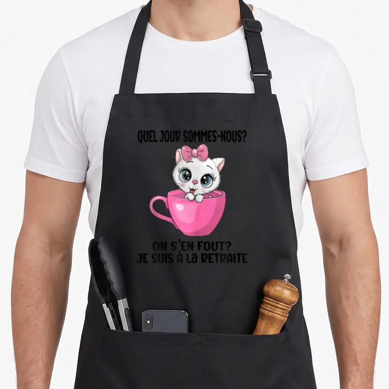 Tablier de cuisine noir avec chat blanc dans une tasse rose et texte humoristique sur la retraite.