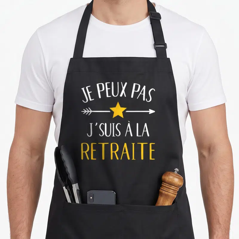 Tablier de cuisine noir avec le texte Je peux pas j'suis à la retraite et une étoile jaune au centre.