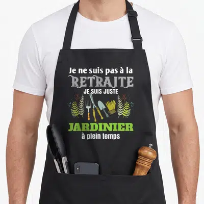 Tablier de cuisine noir avec inscription Je ne suis pas à la retraite je suis jardinier à plein temps et outils de jardinage colorés.