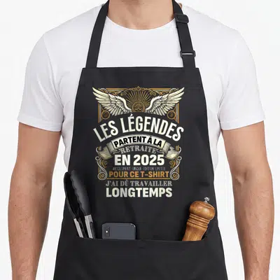 Tablier de cuisine noir avec inscription Les Légendes Partent à la Retraite en 2025 et illustration d'ailes dorées.