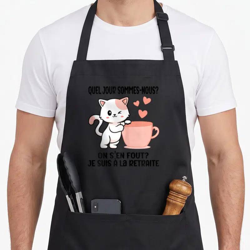 Tablier de cuisine noir avec un chat blanc et rose tenant une tasse rose et le texte On s'en fout je suis à la retraite.