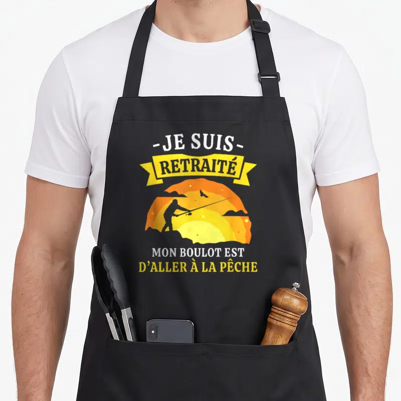 Tablier de cuisine noir avec silhouette pêcheur au coucher de soleil et texte Je suis retraité mon boulot est d'aller à la pêche.