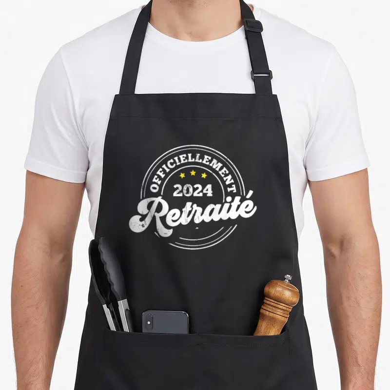 Tablier de cuisine noir avec inscription « Officiellement Retraité 2024 » et trois étoiles jaunes en cercle.